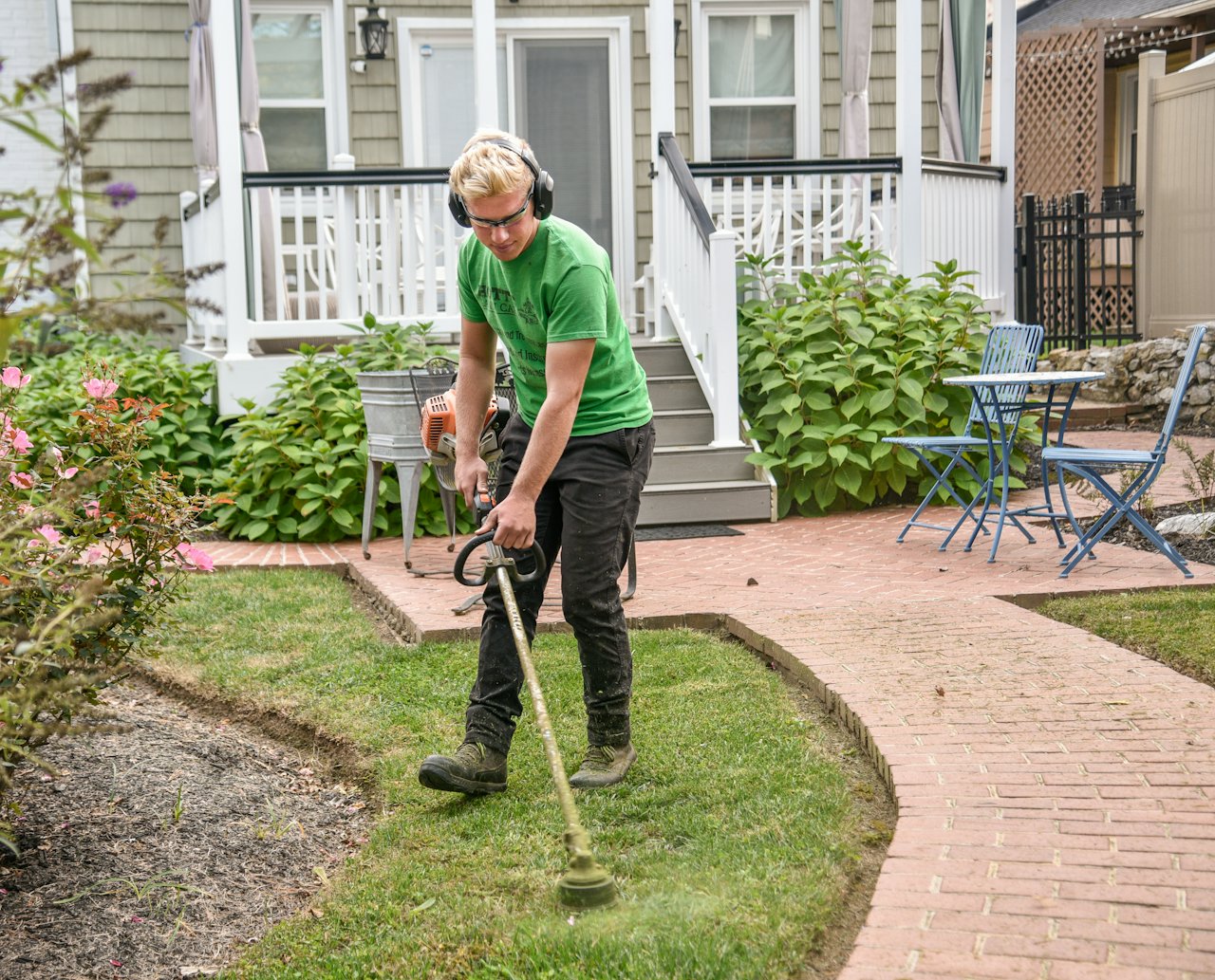 Lawn care professional trimming and edging the border of a residential yard